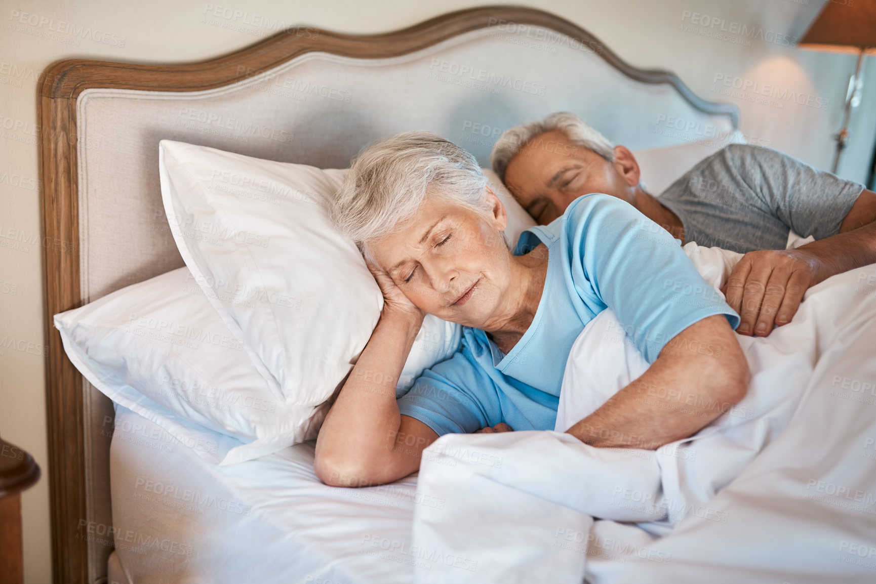 Buy stock photo Cropped shot of an affectionate senior couple cuddling each other while asleep in bed at a nursing home