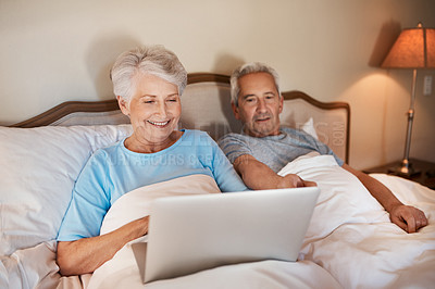 Buy stock photo Cropped shot of a happy senior woman using a laptop and sitting in bed with her husband at home