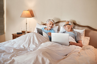 Buy stock photo Cropped shot of a senior couple sitting in bed together and using technology in a nursing home
