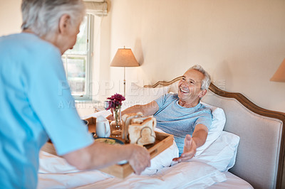Buy stock photo Cropped shot of a senior woman serving her happy husband breakfast in bed in their nursing home