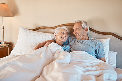 Buy stock photo Cropped shot of an affectionate senior couple lying in bed and holding each other in their nursing home