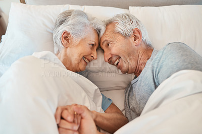 Buy stock photo Cropped shot of an affectionate senior couple looking at each other lovingly while laying in bed in their nursing home