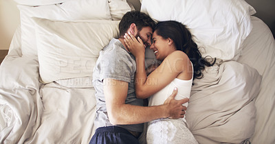 Buy stock photo Shot of an affectionate young couple embracing in bed at home