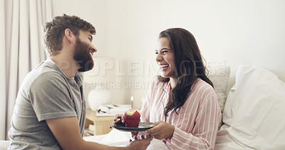 Buy stock photo Shot of a young man surprising his wife with a cupcake in bed at home