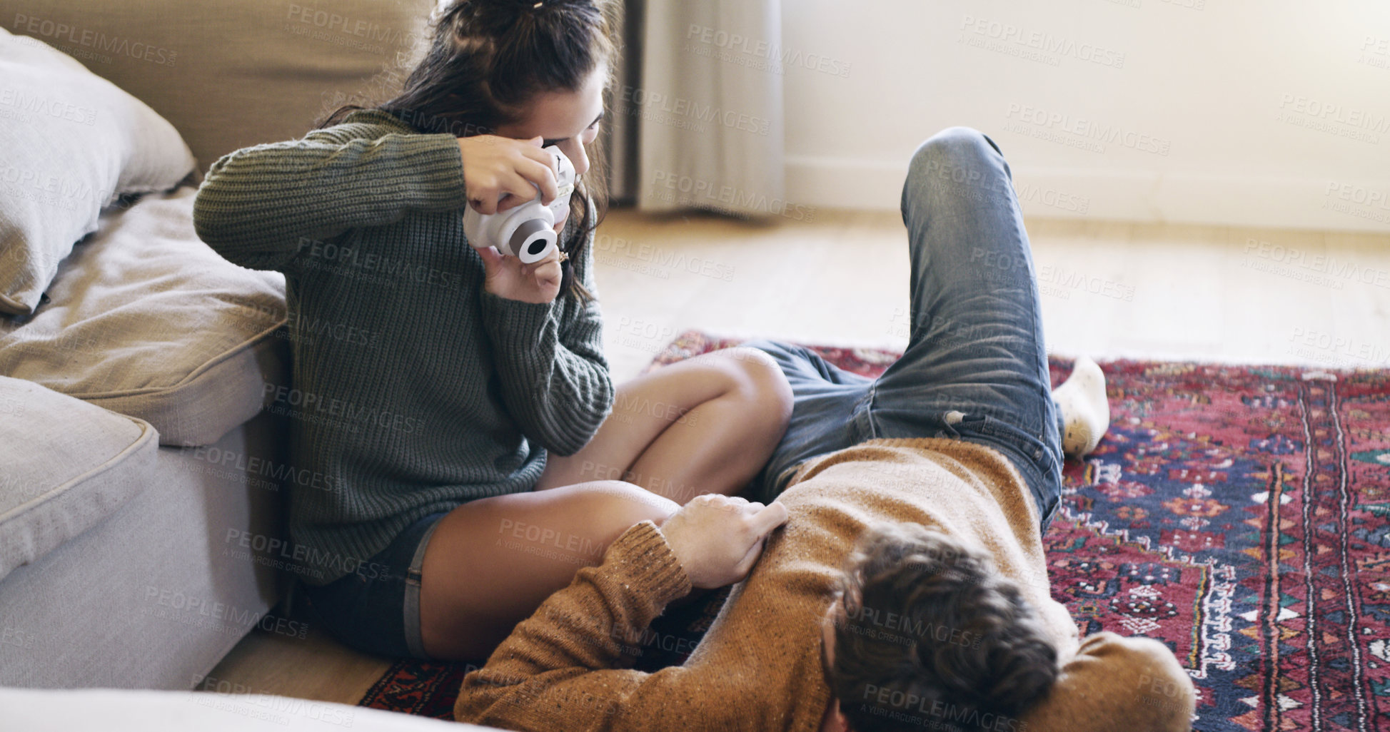 Buy stock photo Shot of a happy young couple taking pictures of each other with a camera at home