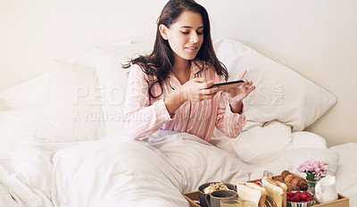 Buy stock photo Shot of a beautiful young woman taking a picture of her breakfast in bed at home