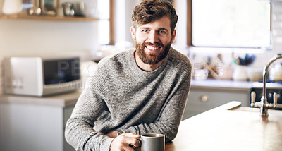 Buy stock photo Shot of a handsome young man having a cup of coffee in the kitchen at home