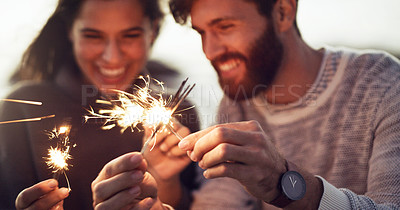 Buy stock photo Cropped shot of a young couple holding sparklers on the beach