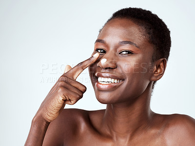 Buy stock photo Studio portrait of a beautiful young woman applying moisturiser against a grey background