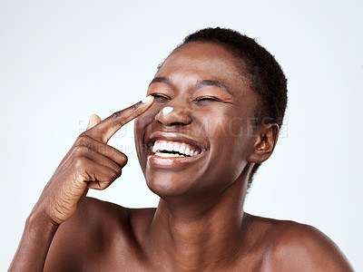 Buy stock photo Studio shot of a beautiful young woman applying moisturiser against a grey background
