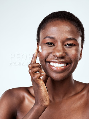 Buy stock photo Studio portrait of a beautiful young woman applying moisturiser against a grey background
