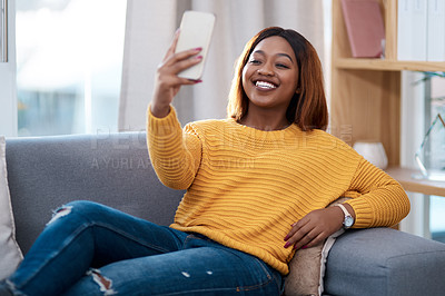 Buy stock photo Black woman, happy in selfie and relax on couch in lounge, lifestyle influencer at home and social media post. African female content creator in apartment, smile in picture and communication on app