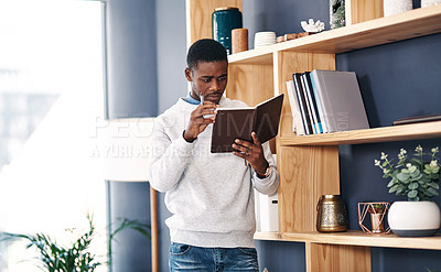 Buy stock photo Shot of a young businessman reading a notebook in a modern office