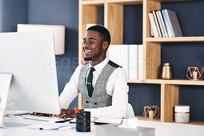 Buy stock photo Shot of a young businessman using a computer at his desk in a modern office