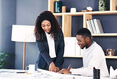 Buy stock photo Shot of a young businessman and businesswoman going over paperwork in a modern office