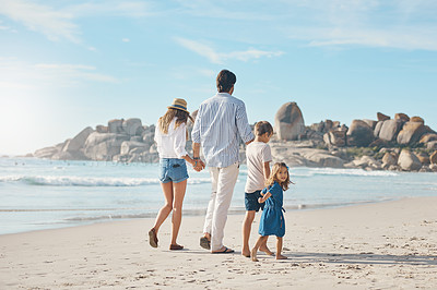 Buy stock photo Rearview shot of an unrecognizable couple holding hands with their two young children and walking along the beach