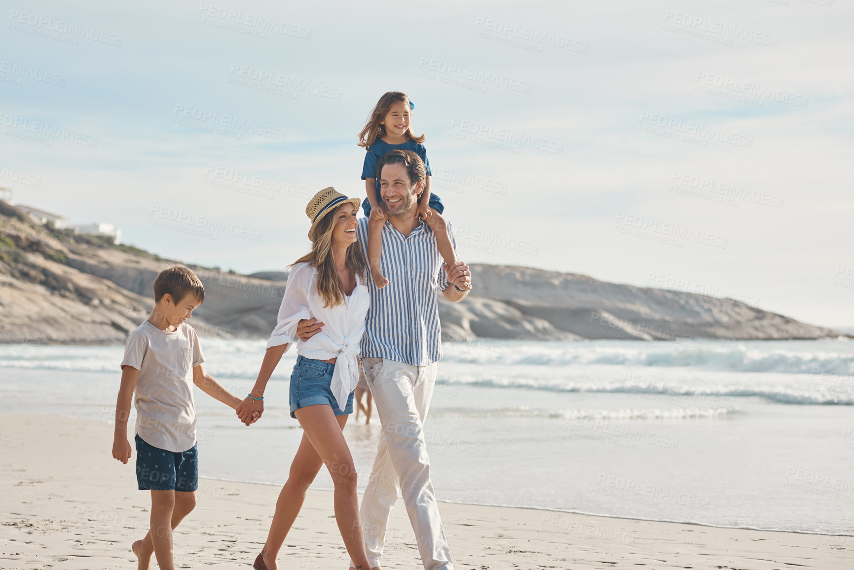 Buy stock photo Cropped shot of an affectionate couple holding hands with their two young children and walking along the beach