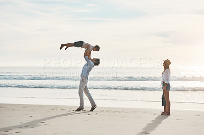 Buy stock photo Full length shot of a happy young couple bonding with their two young children during a day on the beach