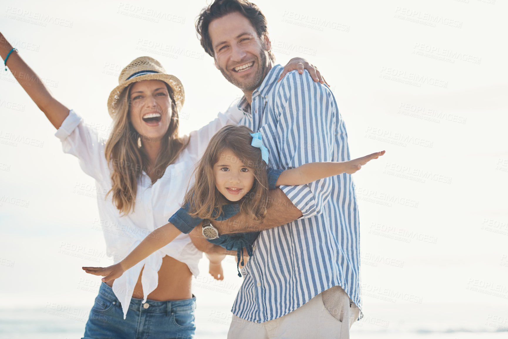 Buy stock photo Cropped portrait of an affectionate couple playing with their daughter during an enjoyable day out on the beach