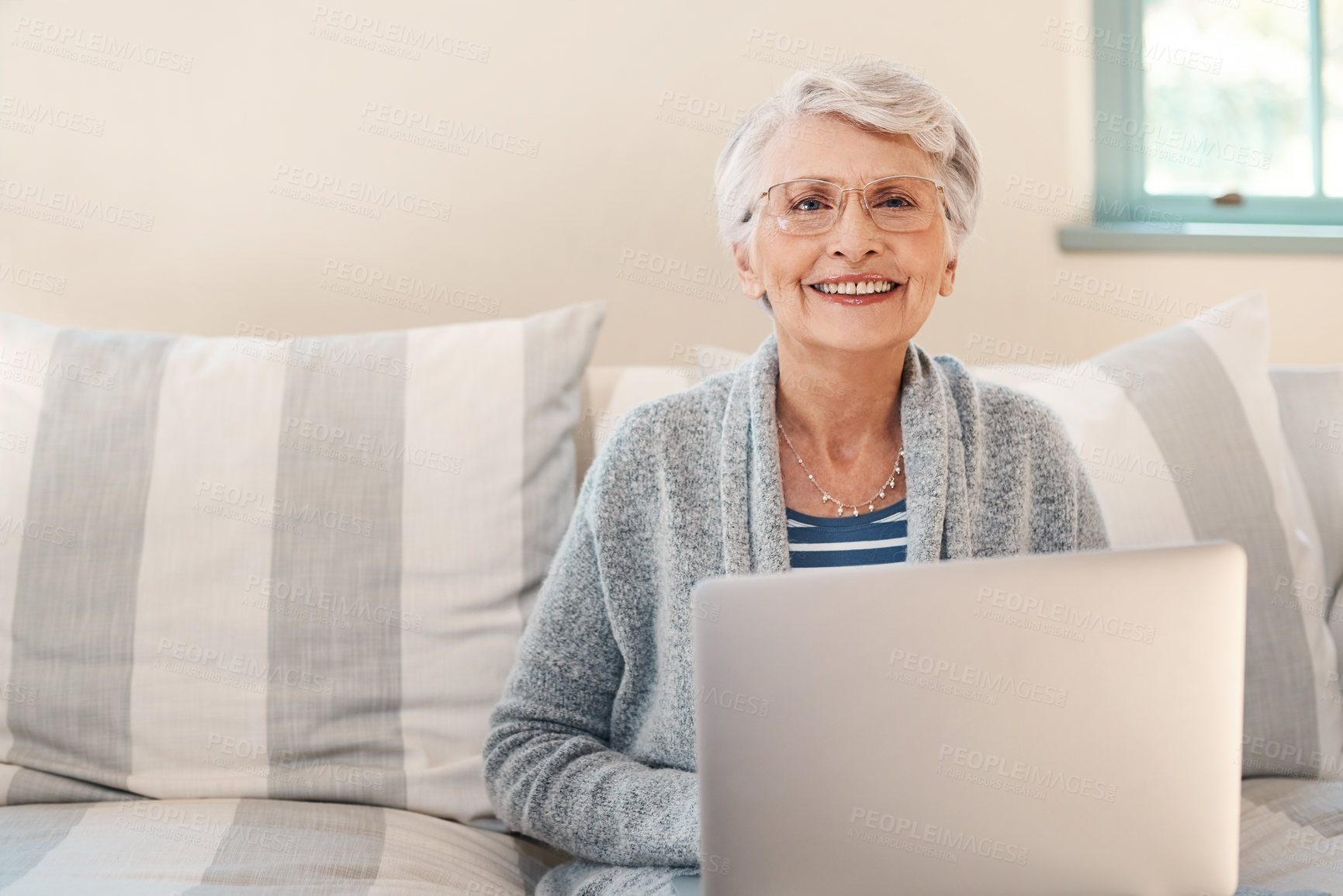 Buy stock photo Shot of a senior woman using a laptop on the sofa at home