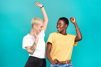 Buy stock photo Studio shot of two young women dancing together against a turquoise background