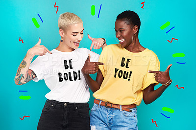 Buy stock photo Studio shot of two confident young women pointing at their statement t shirts against a turquoise background