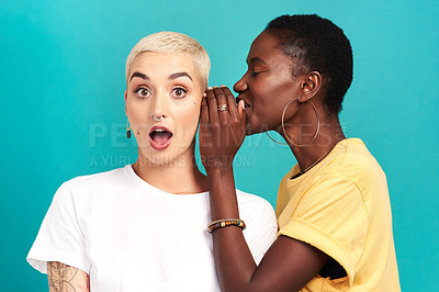 Buy stock photo Studio shot of a young woman whispering in her friend’s ear against a turquoise background