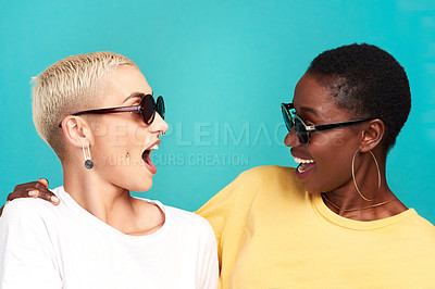 Buy stock photo Studio shot of two young women wearing sunglasses against a turquoise background