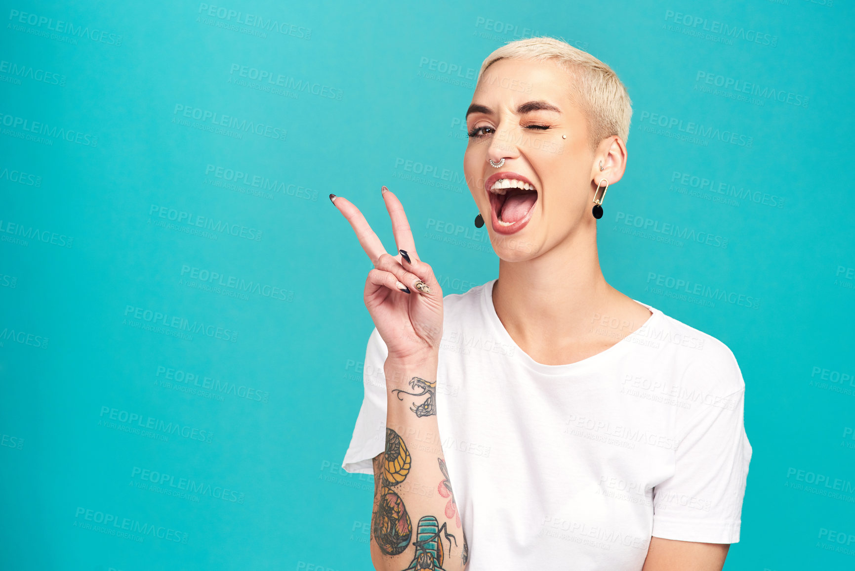 Buy stock photo Studio shot of a confident young woman making a peace gesture against a turquoise background