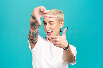 Buy stock photo Studio shot of a confident young woman making a finger frame of her face against a turquoise background