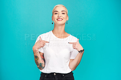 Buy stock photo Studio shot of a confident young woman pointing at her t shirt against a turquoise background