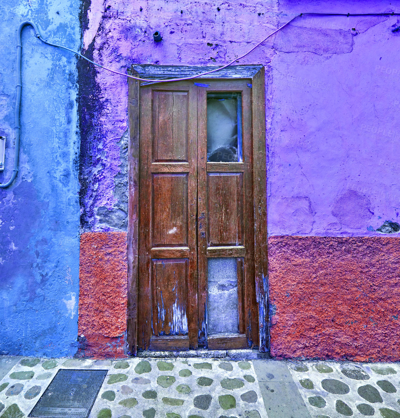 Buy stock photo Old damaged wooden door and vibrant purple wall. Vintage weathered and damaged entrance to a colorful house in a small village or town. Antique and rustic doorway of a vacant home 