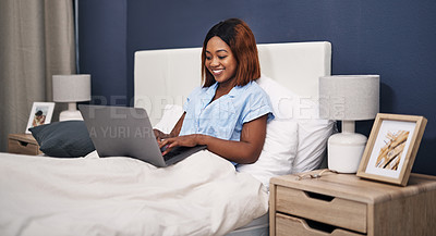 Buy stock photo Cropped shot of an attractive young woman using her laptop while sitting in bed
