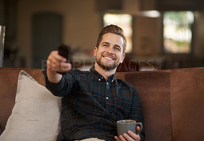 Buy stock photo Relax, coffee and a man watching tv on a sofa in the living room of his home with a remote for streaming. Smile, tea and a happy young male person using a subscription service on his television