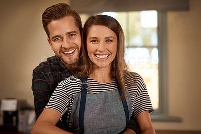 Buy stock photo Love, portrait of couple smiling and hugging from the back in a kitchen of their home. Married or relationship, caring or happy and cheerful or excited man cooking with woman in apron in their house