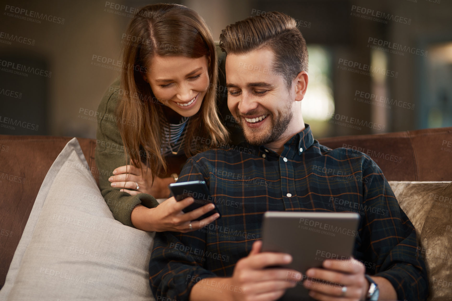 Buy stock photo Happy, sofa and couple with phone and tablet for social media meme, internet joke and show videos. Home, living room and man and woman on technology for website, connection and online chat on weekend