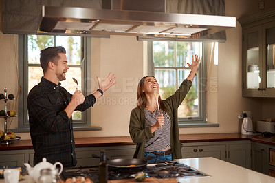 Buy stock photo Food, sing and a funny couple in the kitchen of their home, having fun together while cooking. Karaoke, silly or comic with a man and woman laughing while singing over breakfast in their house