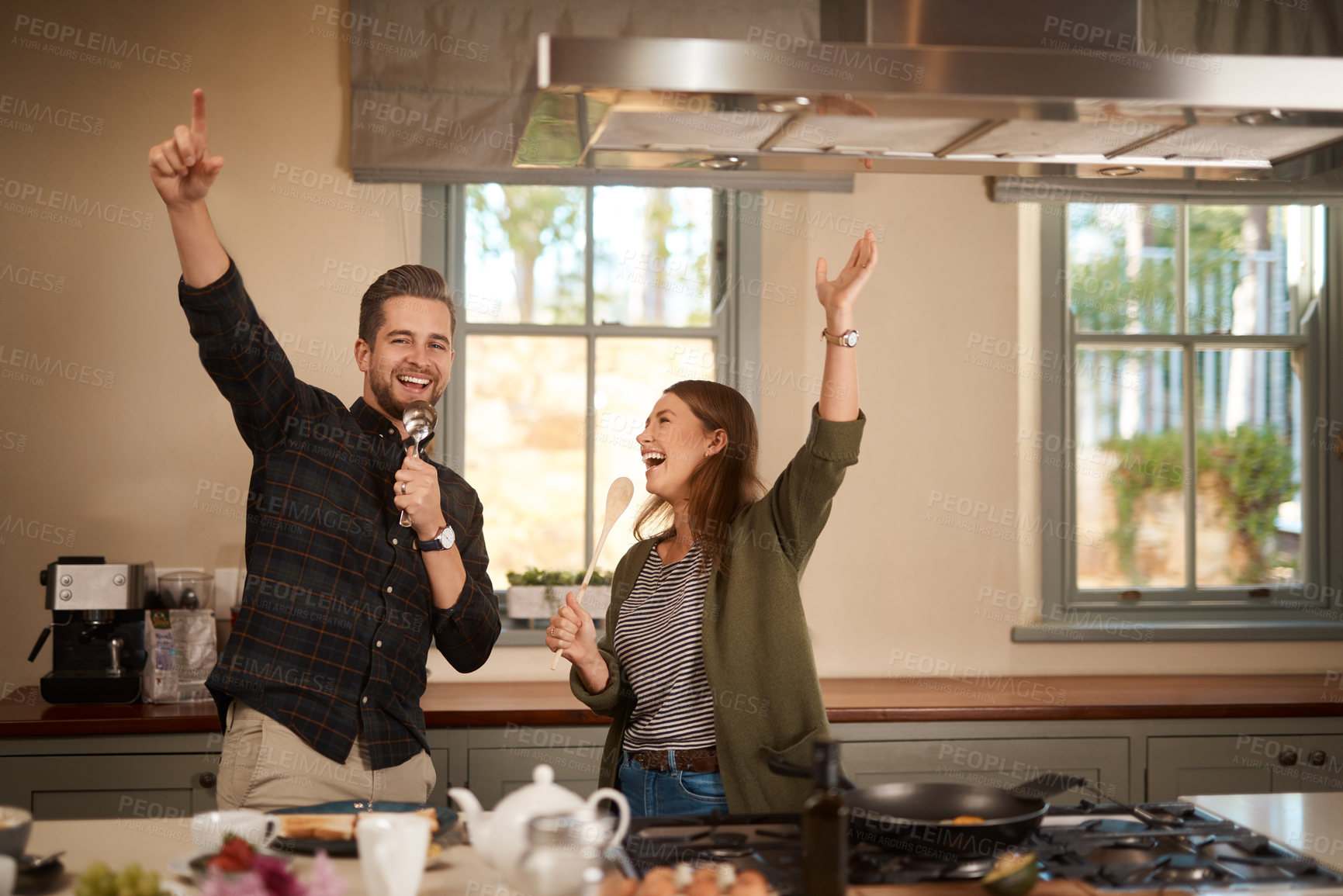 Buy stock photo Food, sing and a funny couple in the kitchen of their home, having fun together while cooking. Karaoke, comic or silly with a man and woman laughing while singing over breakfast in their house