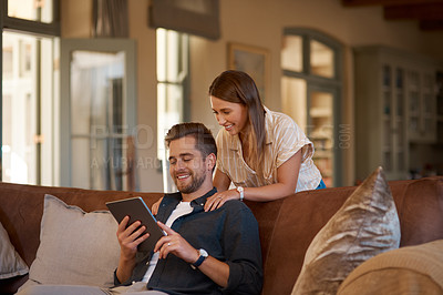 Buy stock photo Cropped shot of a couple using a digital tablet while relaxing at home