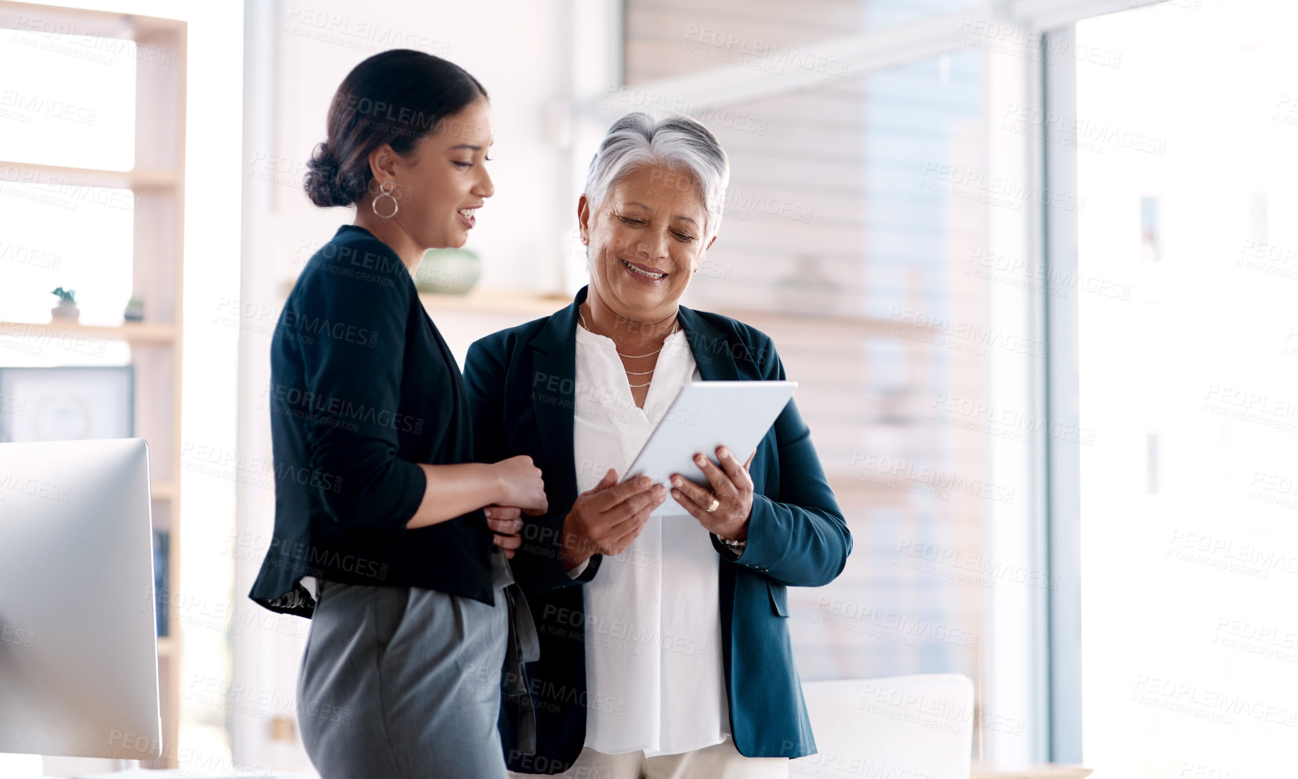 Buy stock photo Shot of two businesswomen working together on a digital tablet in an office