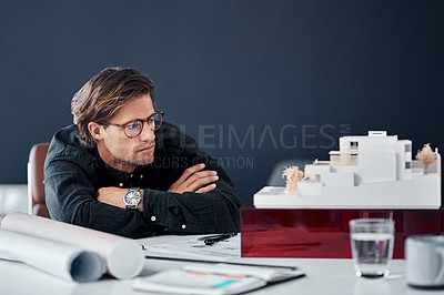 Buy stock photo Shot of a handsome young architect looking at a scale model of a modern house in his office