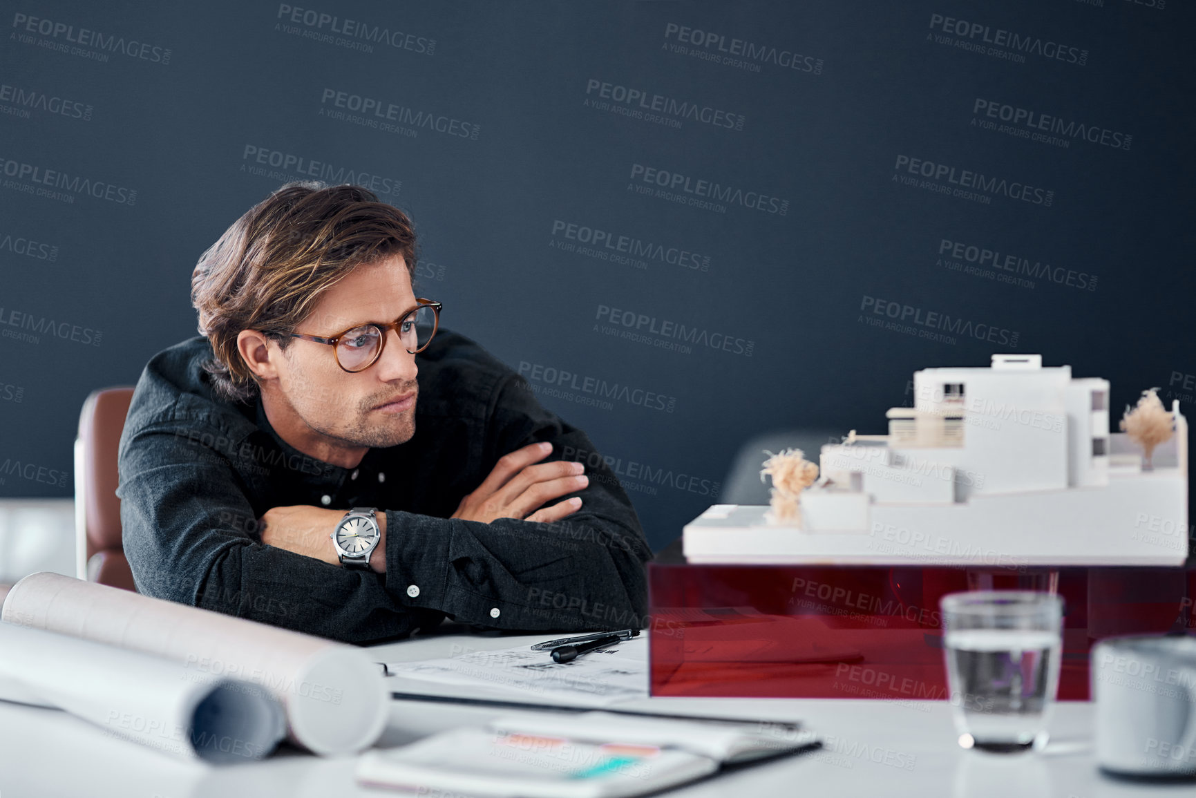 Buy stock photo Shot of a handsome young architect looking at a scale model of a modern house in his office
