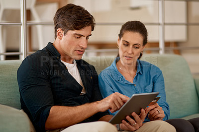 Buy stock photo Cropped shot of a couple using a digital tablet while relaxing together at home