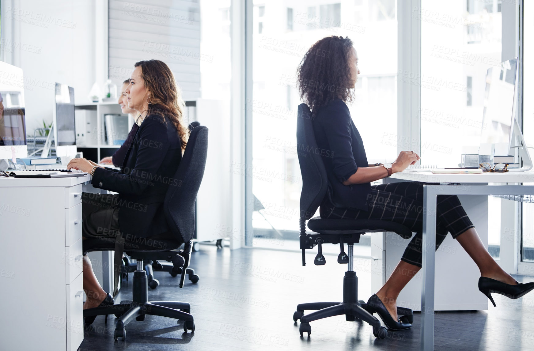 Buy stock photo Shot of a group of young businesswomen using their computers in a modern office