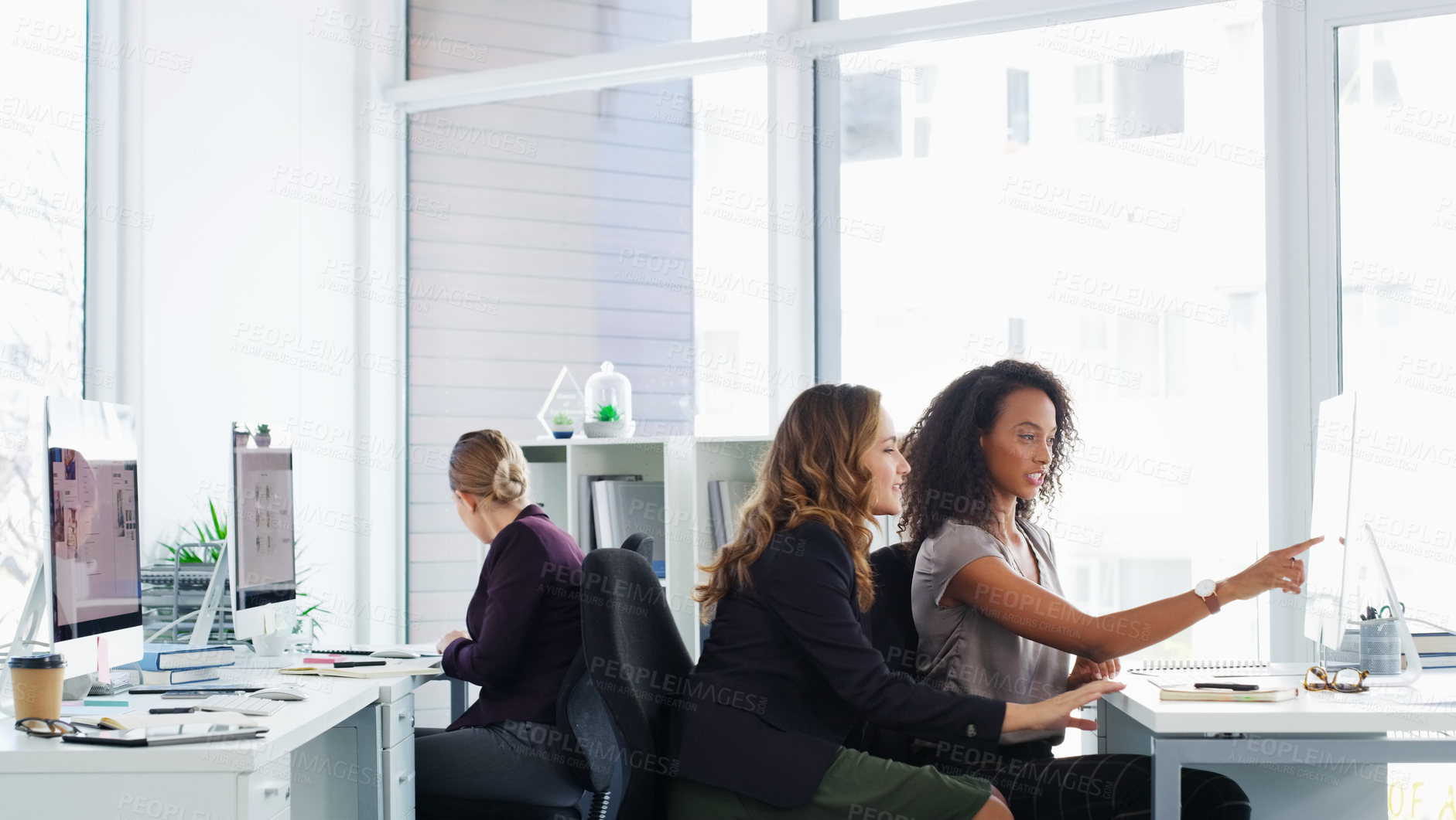 Buy stock photo Shot of two young businesswomen using a computer together in a modern office