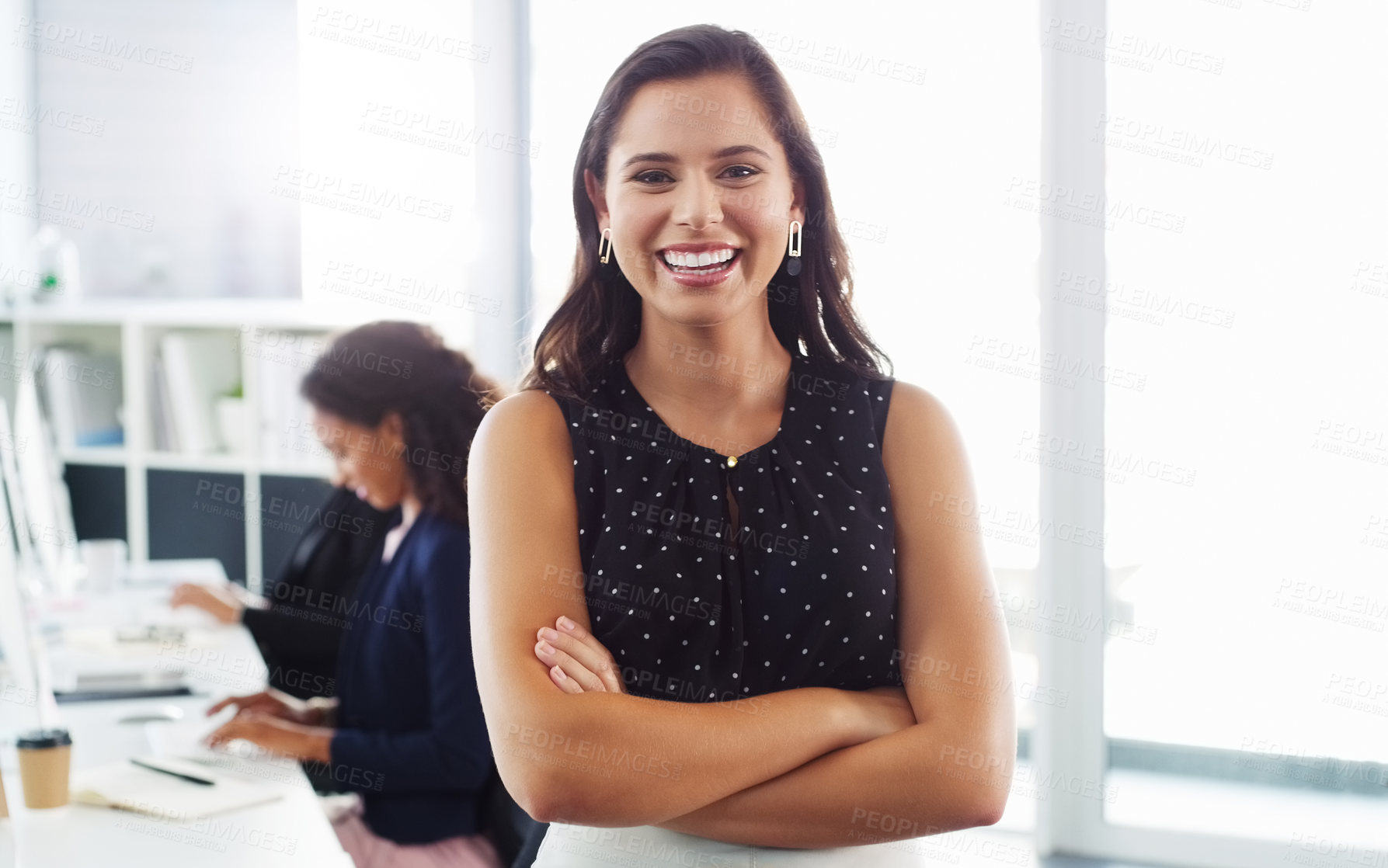 Buy stock photo Portrait of a confident young businesswoman working in a modern office with her colleague in the background