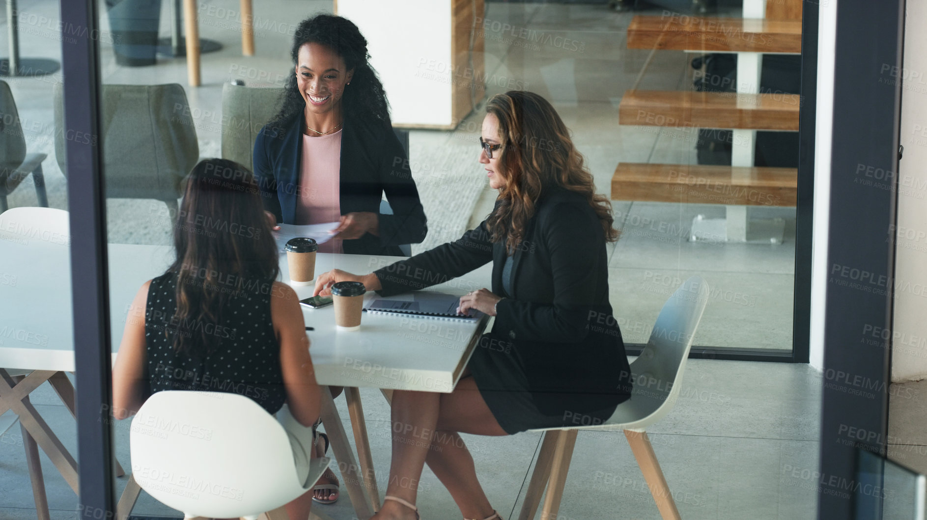 Buy stock photo High angle shot of three young businesswoman sitting in the boardroom during a management meeting