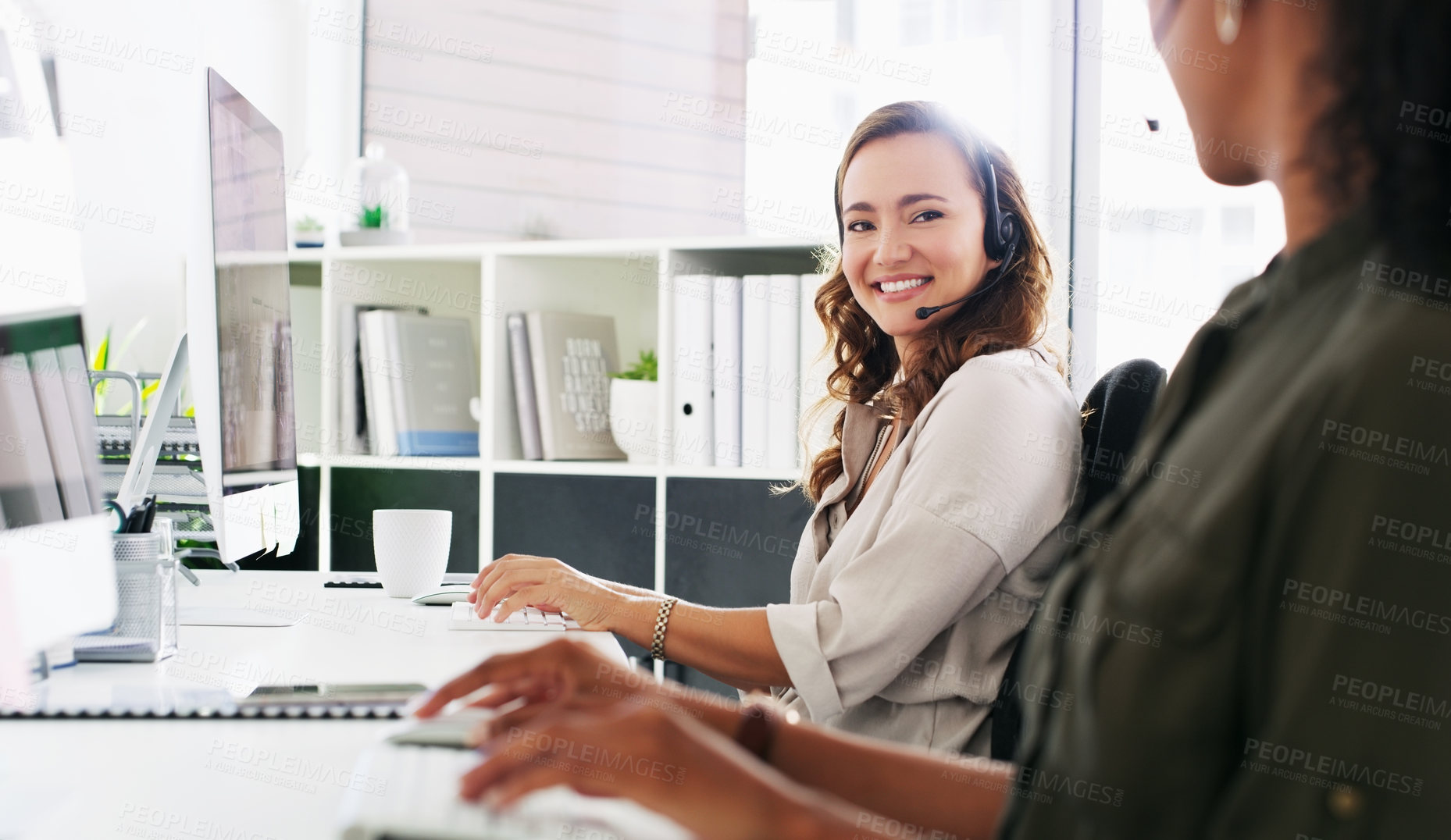 Buy stock photo Shot of a young woman using a computer and headset in a modern office