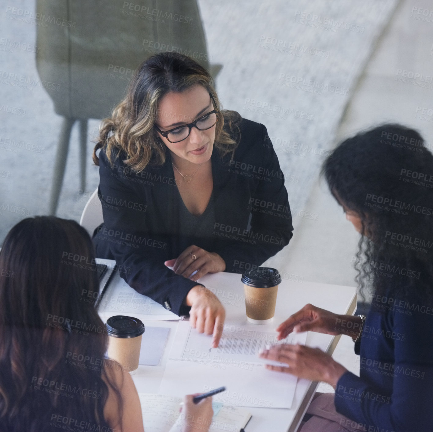 Buy stock photo High angle shot of three young businesswoman sitting in the boardroom during a management meeting