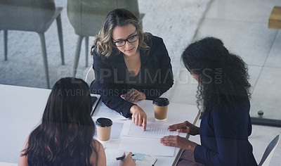 Buy stock photo High angle shot of three young businesswoman sitting in the boardroom during a management meeting